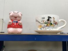 A large Alice in Wonderland cup and saucer and a novelty pig cookie jar