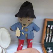 A Paddington bear soft toy figure featuring black hat and red Dunlop Wellington boots.