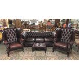 A leather suite comprising Chesterfield sofa, 2 wing armchairs and a foot stool.