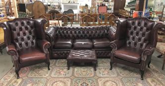 A leather suite comprising Chesterfield sofa, 2 wing armchairs and a foot stool.