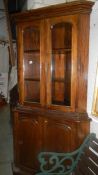 A tall mahogany corner cabinet with glazed doors to top and panelled doors to bottom.