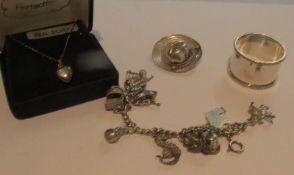 A silver heart pendant, a silver charm bracelet, a silver sombrero brooch and a silver napkin ring,