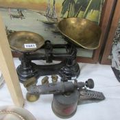 A set of kitchen scales with weights and a blow lamp.