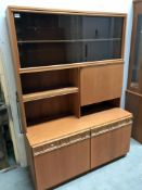 A wall unit with sliding glass and a drinks cabinet and drawers