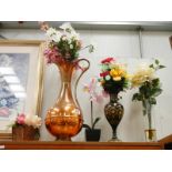 A large copper jug and gilded black metal vase with artificial flowers