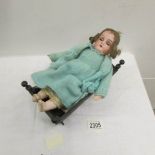 A small Victorian porcelain headed doll (a/f) and an old wooden rocking cradle.