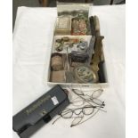 A box of miscellaneous collectables including WW1 brass button cleaners, vintage spectacles,