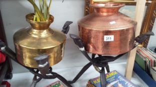 A copper and a brass planter on African folding wood stands