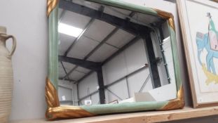 A large mirror with green frame with gold scroll corner detail