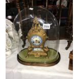 A French style mantel clock featuring porcelain face and panel under glass dome