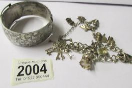 A silver charm bracelet and an Edwardian silver bangle (tested).