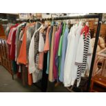 A rail of vintage and modern clothing including shirts, coats, dresses, jackets etc.