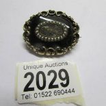 An oval mourning brooch set with jet and half seed pearls around a plaited hair centre (centre
