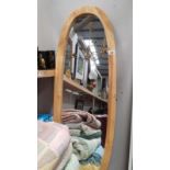 An oval mirror in pine surround