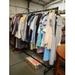 A rail and box of vintage and modern clothing including shirts, coats, dresses, jackets etc.