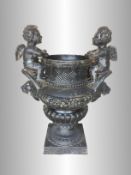 A garden urn with cherubs on either side and lion's head features, approximate height 45".