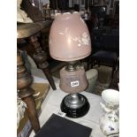 A 20th century oil lamp with pink glass shade and vessel