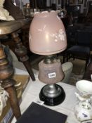 A 20th century oil lamp with pink glass shade and vessel