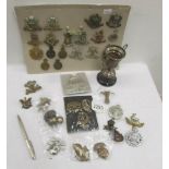 A mixed lot of cap badges together with a silver biro and a silver trophy.