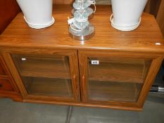 A teak effect cabinet with bevelled glass doors