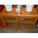 A teak effect cabinet with bevelled glass doors