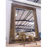 An ornate gilt framed mirror with bevel edge.