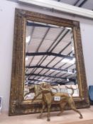 An ornate gilt framed mirror with bevel edge.