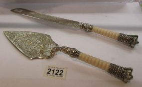 An ornate cake slice with matching cake knife having crown finials.