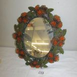 A vintage oval mirror with beadwork frame.