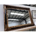 A wall mounted bevel edge mirror with ornate frame