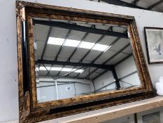 A wall mounted bevel edge mirror with ornate frame