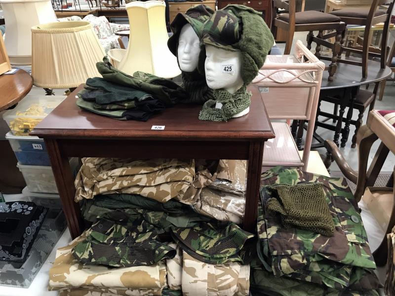 A large quantity of UK combat clothing including boiler suits, T-Shirts, jackets and hats etc.