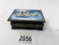 A Russian lacquered snuff box depicting a winter scene with white horses pulling a carriage.