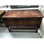 An Edwardian oak blanket box on legs with draped carving to front and gothic iron hinges to lid