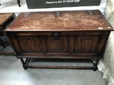 An Edwardian oak blanket box on legs with draped carving to front and gothic iron hinges to lid