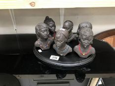 A quantity of African busts on a plinth