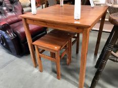 A stained pine kitchen table with 2 stools