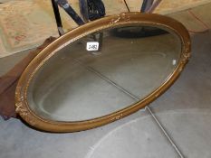 An oval gilt framed mirror.