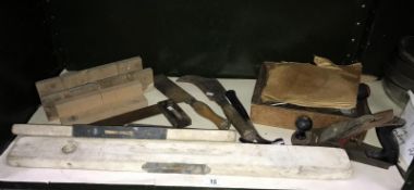 A shelf of tools including spirit levels, plane etc.