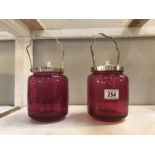 A pair of cranberry glass lidded canisters