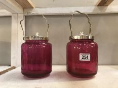 A pair of cranberry glass lidded canisters