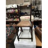 A small dark wood kitchen chair with bergere seat