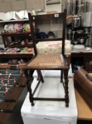 A small dark wood kitchen chair with bergere seat