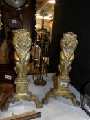 A pair of brass fire dogs as lion figures and a brass companion set.