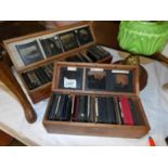 Two wooden boxes containing approximately 175 black and white glass lantern slides of subjects