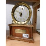 An oak and brass clock with brass plaque to front reading 'La Mysteriouse'.
