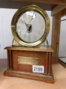 An oak and brass clock with brass plaque to front reading 'La Mysteriouse'.