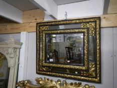 A 19th century French ebony mirror with gilt repousse' brass, approximately 71 x 84 cm.