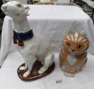 A ceramic figure of a greyhound dog and a ceramic figure of a ginger cat.