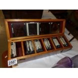 A wooden box containing approximately 70 black and white glass lantern slides of historic